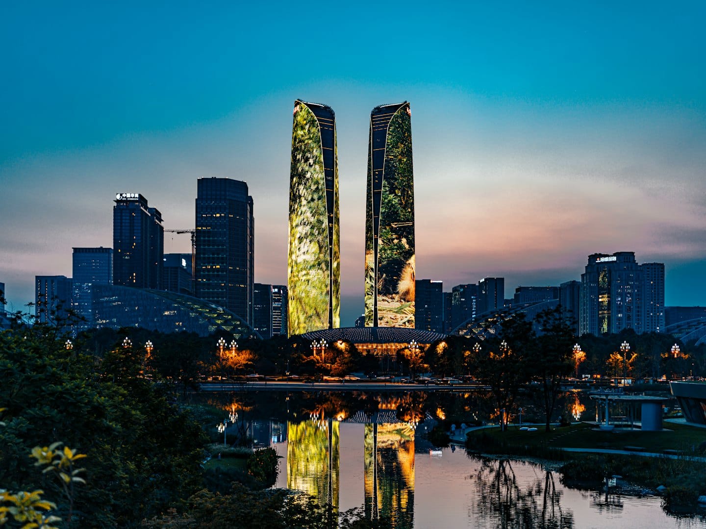 Due grattacieli illuminati si riflettono sul lungomare della città al tramonto.