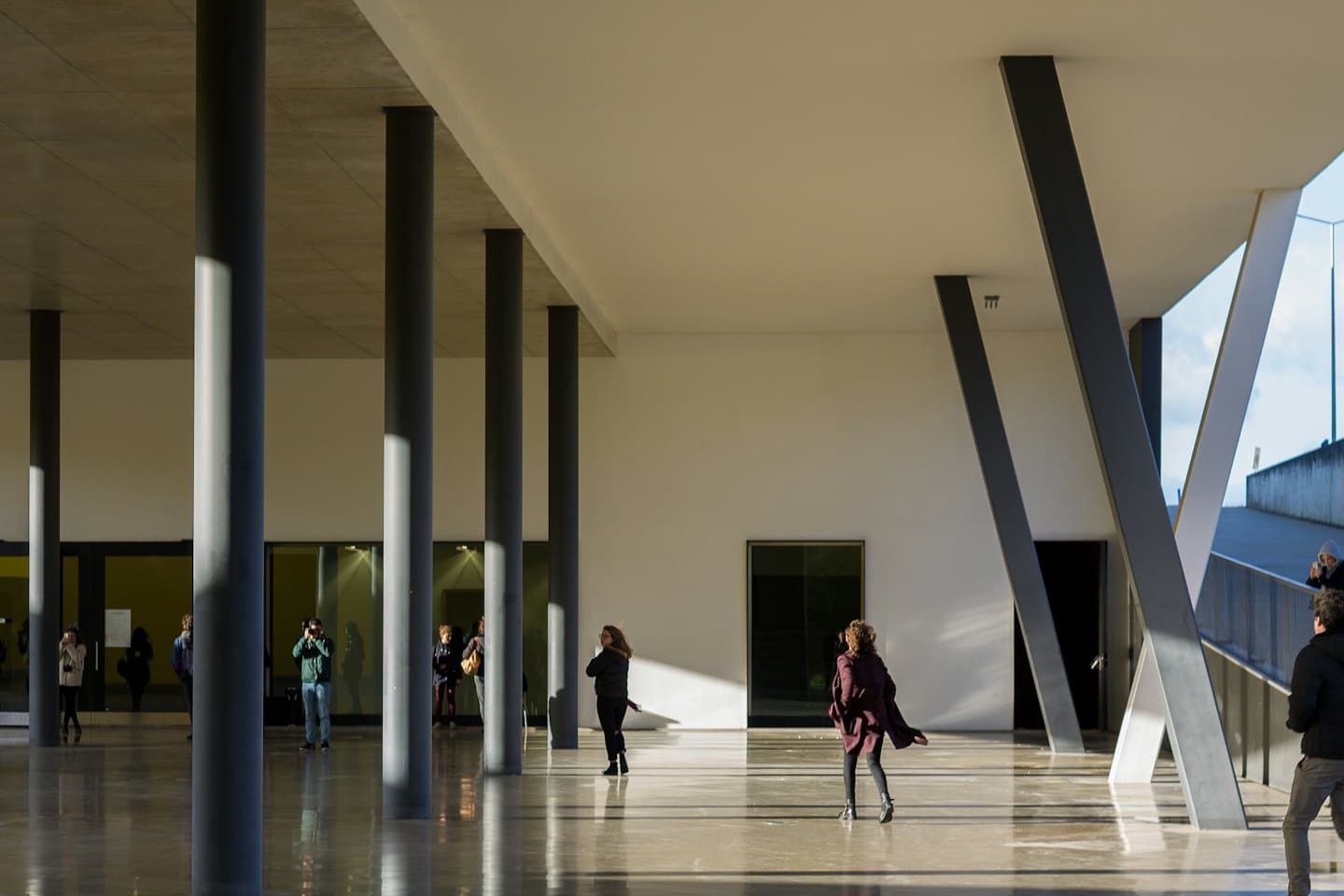 Gruppo eterogeneo esplora un edificio moderno con grandi colonne.